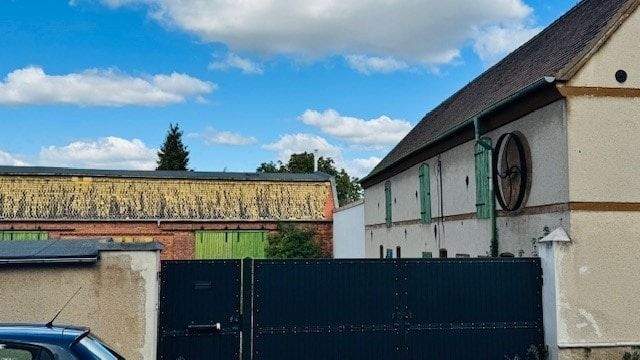 Einzäunung: Mauer mit Tor und zwei Scheunen