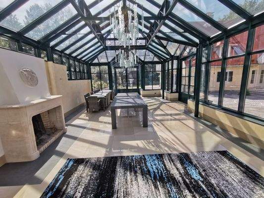 Lichtdurchflutete Orangerie mit Kamin und Essbereich unter Glasdach