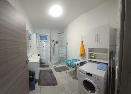 Badezimmer mit Tageslicht, bodenebener Dusche und Waschmaschinenanschluss 
