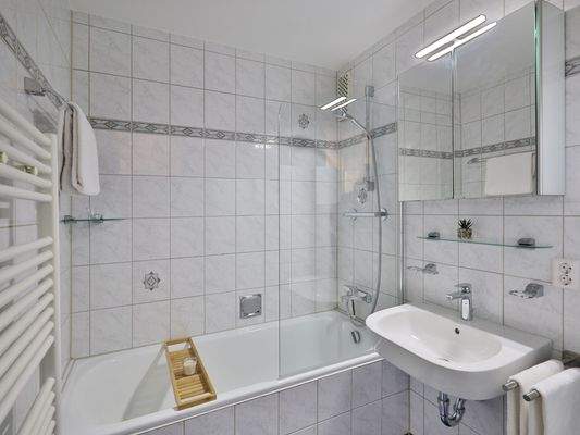 Hell gefliestes Bad mit Duschwanne und Waschmaschinenanschluss