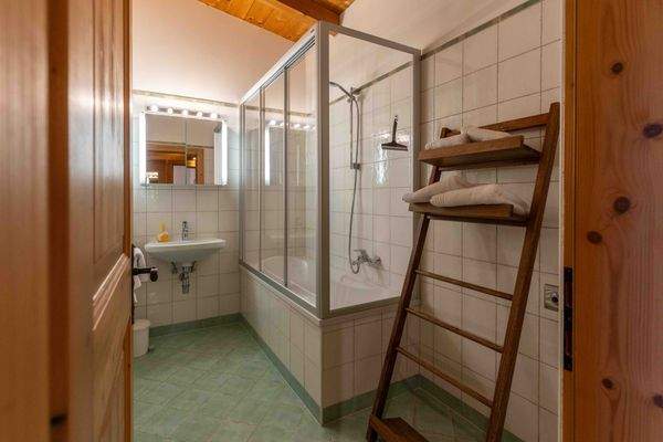 Helles Bad mit Badewanne und Duschkabine, großem Spiegel und praktischem Handtuchhalter im Landhausstil.