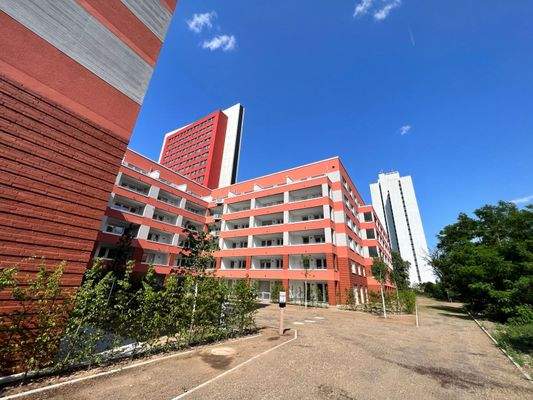 Rückansicht der Mehrfamilienhäuser mit Loggien, umgeben von grünen Sträuchern