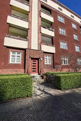 Rotes Backsteingebäude mit grüner Hecke.png