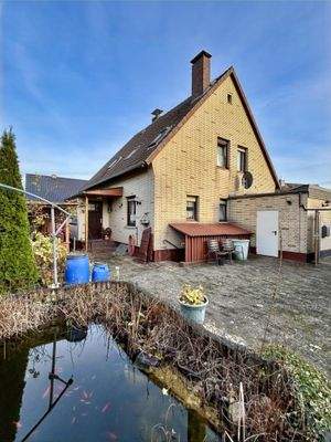 Blick auf den gepflasterten Innenhof mit Gartenteich und den Eingangsbereich des Hauses