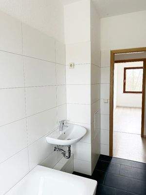 Tageslichtbad mit Wanne, WC und Waschtisch und Blick Richtung Flurbereich