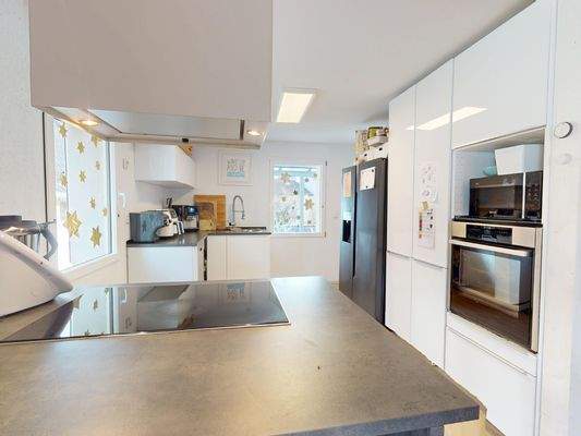 Moderne Einbauküche mit Kochinsel zum Essbereich hin