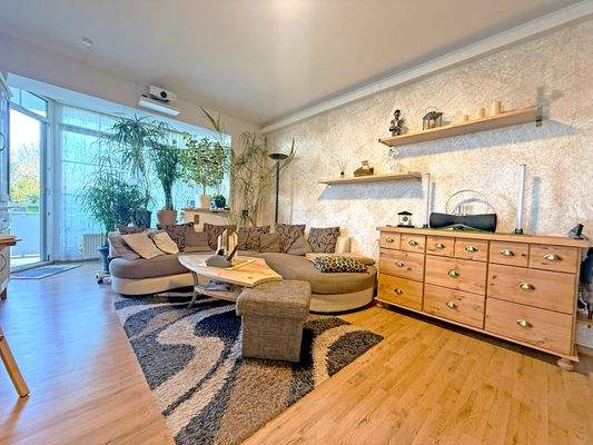 Großzügiges Wohnzimmer mit Zugang zum Balkon und angrenzender Küche