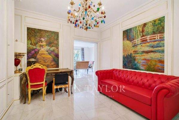 Entrée élégante avec un grand canapé rouge et des œuvres d'art colorées sur les murs.