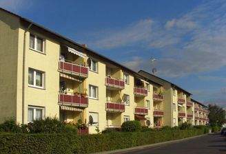 Rückansicht auf das gelb gestrichene Haus mit roten Balkonen.