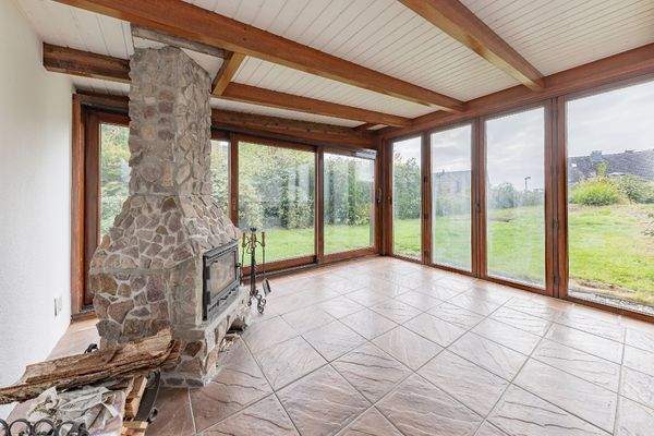 Wintergarten mit grüner Aussicht und Kamin