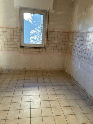 Küche mit untapezierten Wänden, beigen Fliesenspiegel und Bodenfliesen