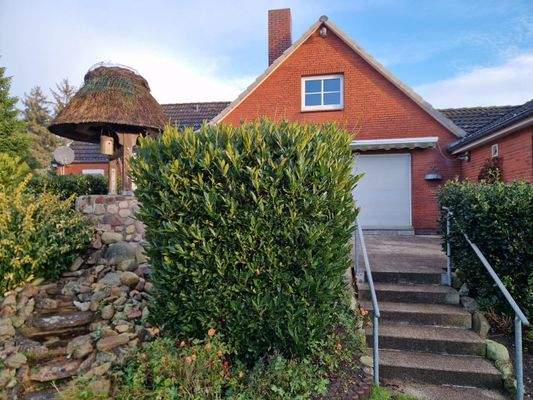 Steintreppe zur Terrasse und links seitlich der Brunnen mit Bachlauf