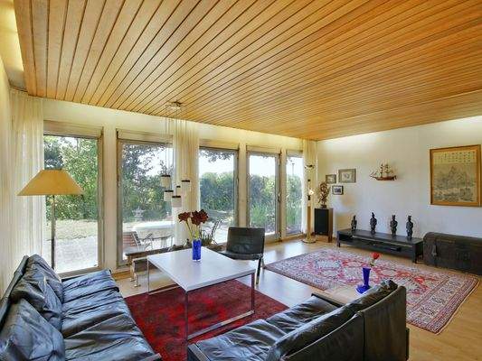 Helles Wohnzimmer mit großer Fensterfront zum ruhigen Garten