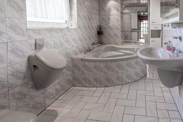 Badezimmer mit Eckbadewanne und Urinal