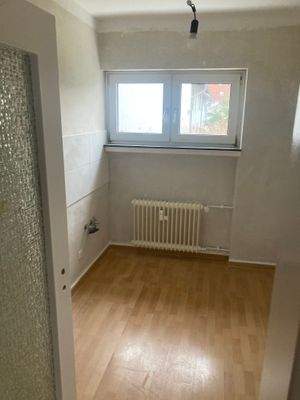 Küche mit Fenster mit tapezierfähigen Wänden und hellem Fliesenspiegel. Es ist ein Vinyl-Boden in Holzoptik verlegt.