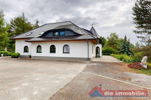 Charaktervolle Fassade mit markanten Rundbogenfenstern umgeben von gepflegtem Grün 