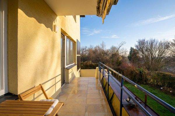 Balkon mit Markise und Stiegen hinunter in den Garten