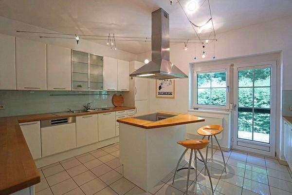 Dan Küche mit Kochinsel, Markeneinbaugeräten und Ausgang in den Garten