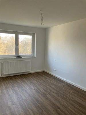 Zimmer mit Fußboden in Holzoptik, doppelten Fenstern und Heizkörpern 