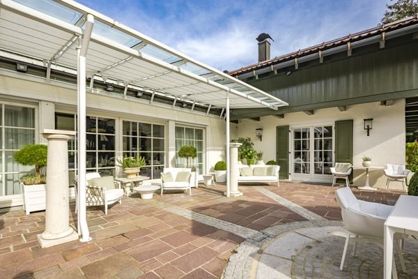 Wohnlicher Wintergarten führt vom Haupthaus ins Gästehaus