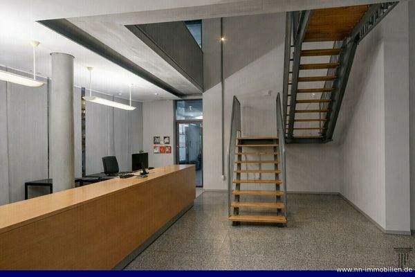 Moderner Empfangsbereich mit Holztheke und offener Treppe zum I. OG