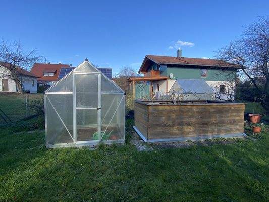 Gewächshaus und Hochbeet im Garten
