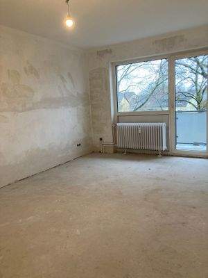 Wohnzimmer mit Zugang zum Balkon und weißem Heizkörper.