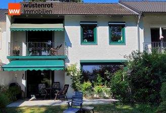 Blick vom Garten auf die Hausrückseite mit Balkon und die schöne Terrasse mit Außenmarkise