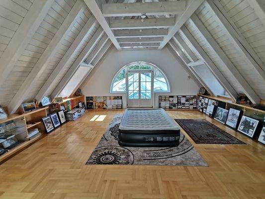 OG: Geräumige Bibliothek mit Dachschrägen, großer Fensterfront und Blick zum Spabereich