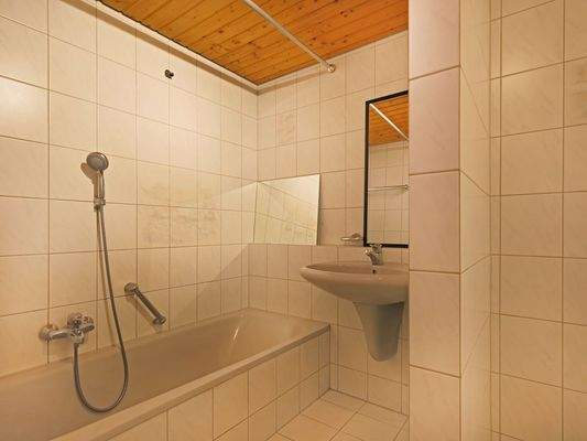 Praktisch aufgeteiltes Badezimmer mit Badewanne und Nische für die Waschmaschine