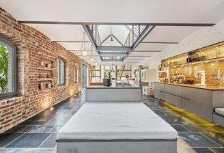 Offene Design-Küche mit Kochinsel und Backsteinwänden