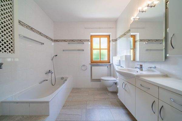 Badezimmer mit hellen Fliesen und klassischer Ausstattung