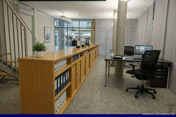 Heller Büro- und Empfangsbereich mit Holzregalen und mgl. Arbeitsplätze