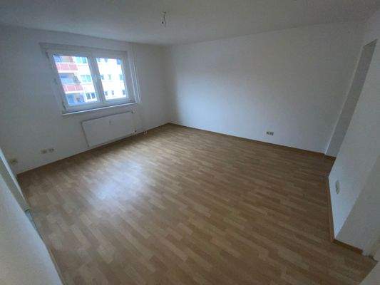 Wohnzimmer mit braunem PVC Boden, weißen Wänden und Fenster.jpg