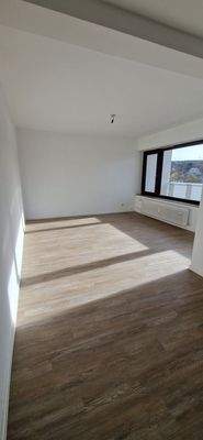 Wohnzimmer mit großer Fensterfront, mit hellem Vinylboden und weißen Wänden.jpg