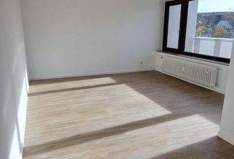 Wohnzimmer mit großer Fensterfront, mit hellem Vinylboden und weißen Wänden.jpg