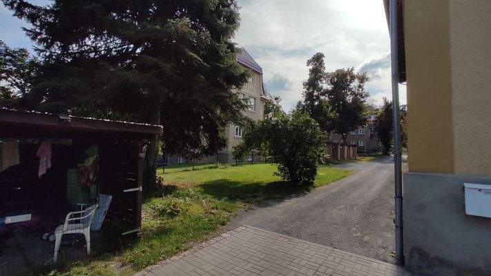 Ansicht hinterer Objekteingang mit Gartenanteil (Carport) und allg. Grünfläche