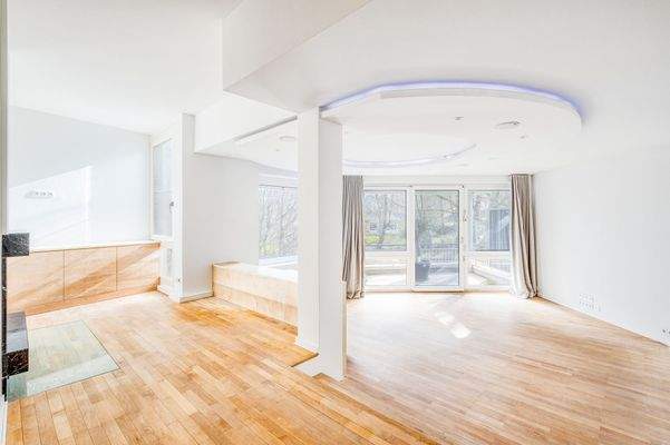 Weitläufiger Wohnsalon mit klarer Raumzonierung und bodentiefen Fenstern