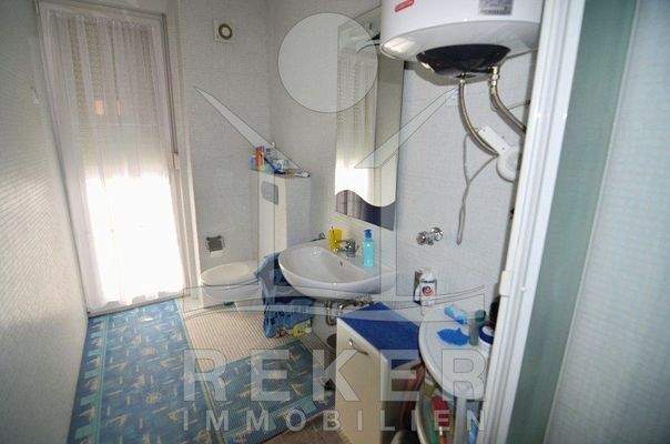 Im hell gefliesten Badezimmer befindet sich der Durchlauferhitzer für die Warmwasseraufbereitung.