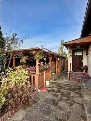 Blick auf den Eingangsbereich und die kleine Gartenlaube mit überdachtem Sitzplatz