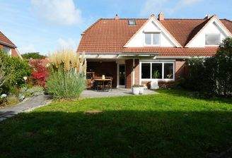 Blick vom Garten auf das Haus und die überdachte Terrasse mit Outdoor-Küche