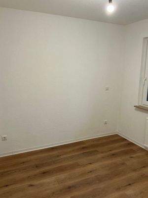 Schlafzimmer mit Bodenbelag in Holzoptik, Wände weiß angelegt