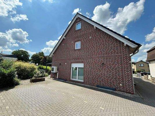 Seitenansicht-Gebäude-mit-Parkplatz-und-Wärmepumpe