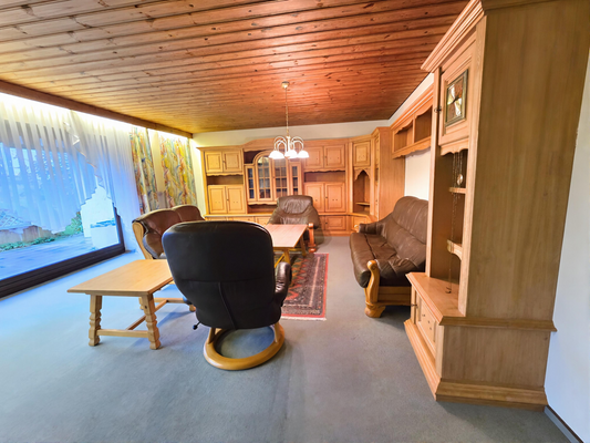 Wohnzimmer mit Bodenfenstern und Blick auf Terasse und Garten.png