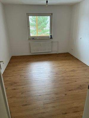 Schlafzimmer mit Fenster. Wände und Decke weiß gestrichen. Neuer Vinylboden in braun.