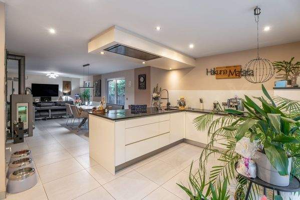 Lichtdurchflutete Wohnküche mit moderner Deckenhaube und nahtlosem Wohn-Essbereich