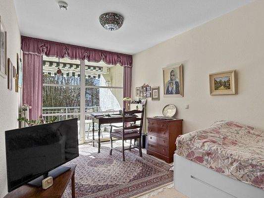 Freundliches Schlafzimmer mit Schiebetür zum Balkon