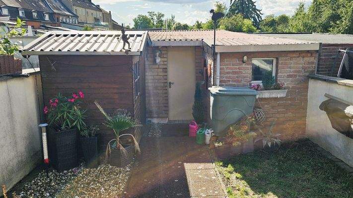 Terasse 1 mit Gartenhaus und Eingang Garage