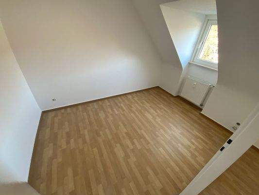 Kinderzimmer mit braunem PVC Boden, weißen Wänden, Dachschräge und Fenster.jpg