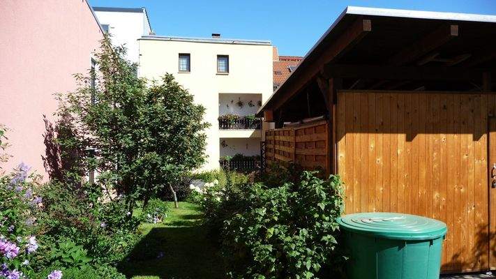 Gebäuderückseite mit Balkonen, Garten und Carport